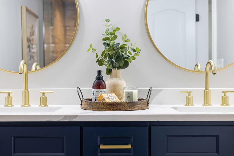 Navy double vanity with brass faucets and round mirrors