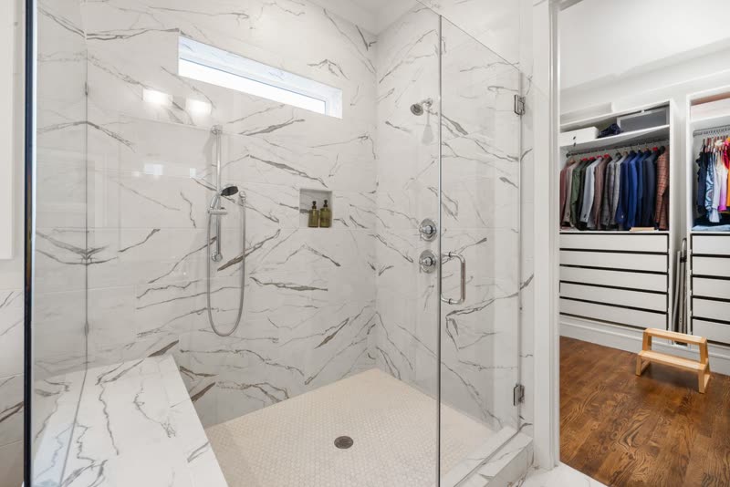 Marble-look walk-in shower with a glass enclosure and built-in bench